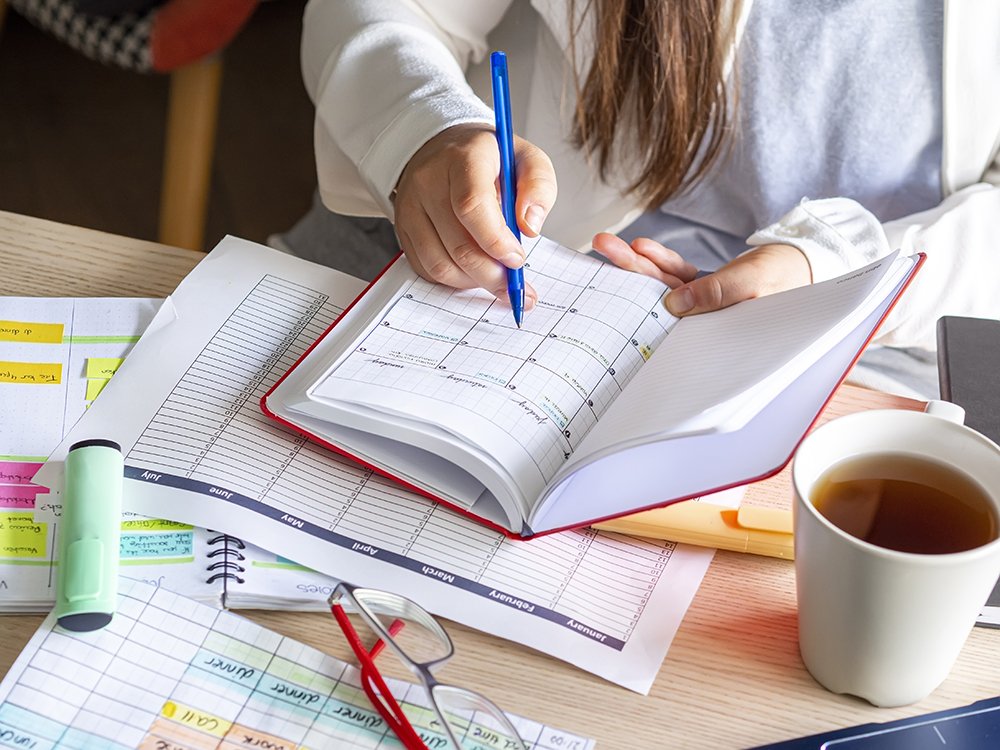Woman scheduling plans in calendar notebook at desk